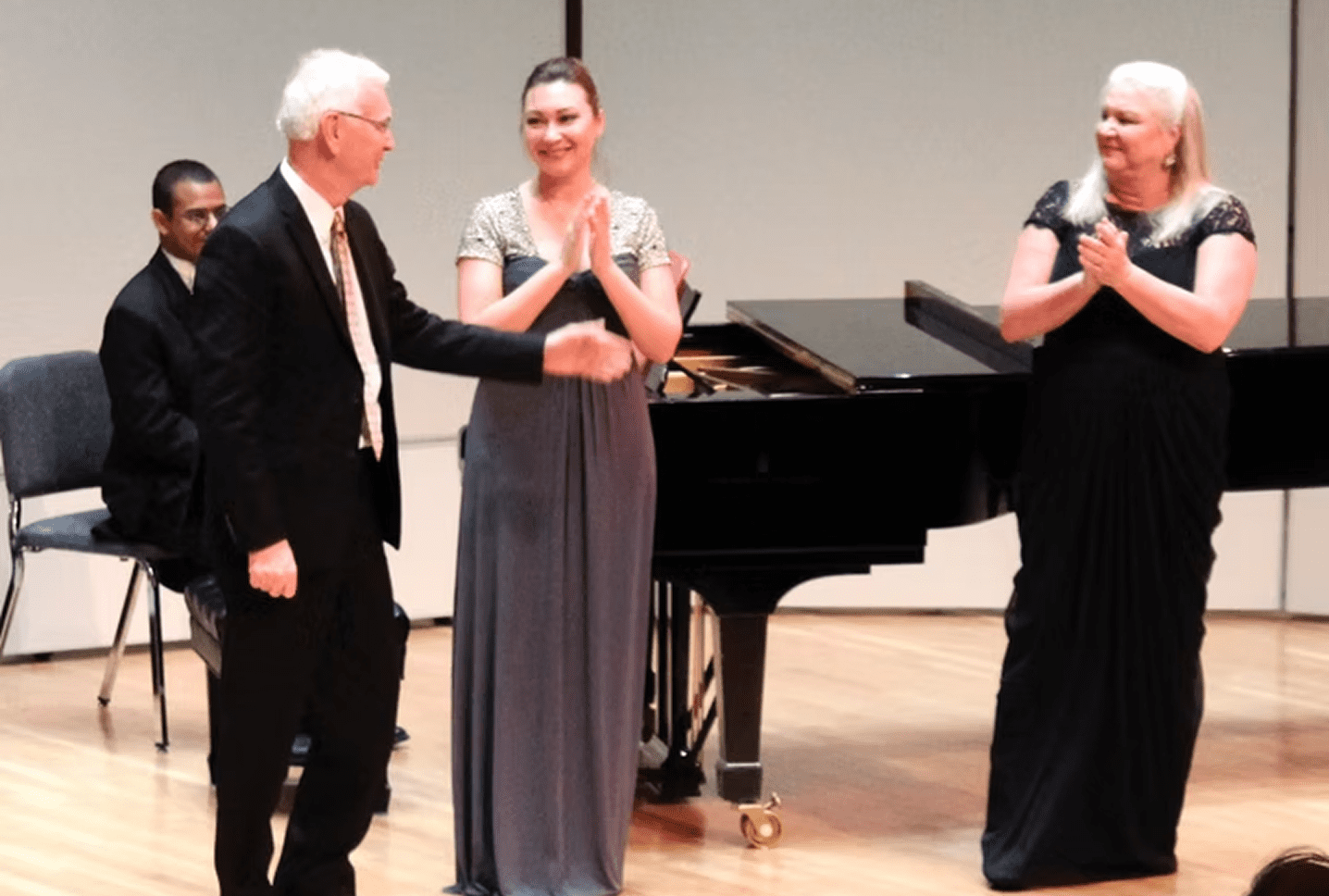 People applauding on stage near piano